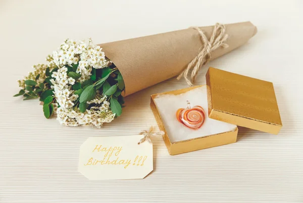 Yellow Birthday Card with Golden Present Box with Glass Heart. Bouquet White Small Flowers in Brown Craft Paper with String