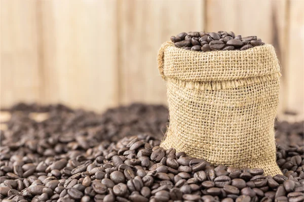 Coffee beans in bag on roasted coffee seed and wooden background