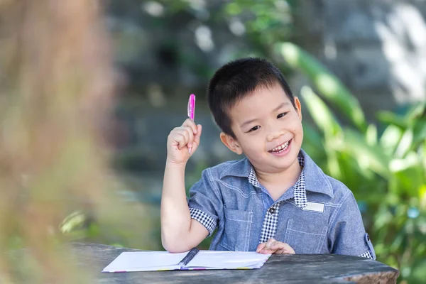 Asian boy use pencil writing on notebook