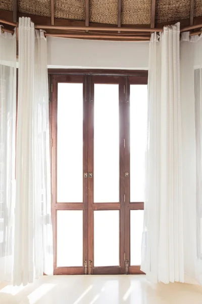 Light shines through white curtains in room