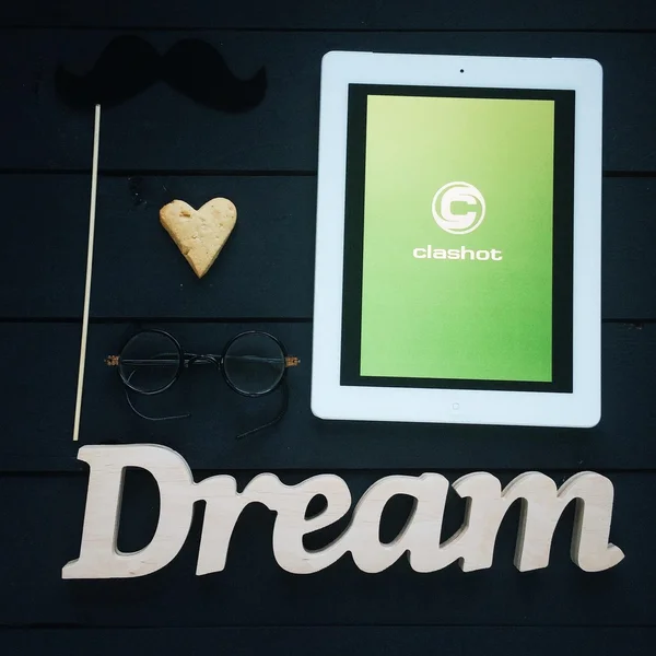 Tablet computer with Clashot logo and accessories on dark wooden background