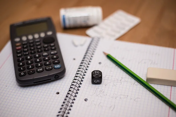 Study place with calculator and painkillers in background