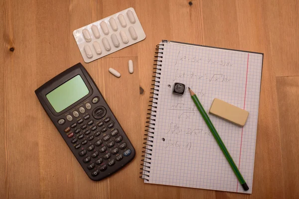 Study place with calculator and painkillers in background