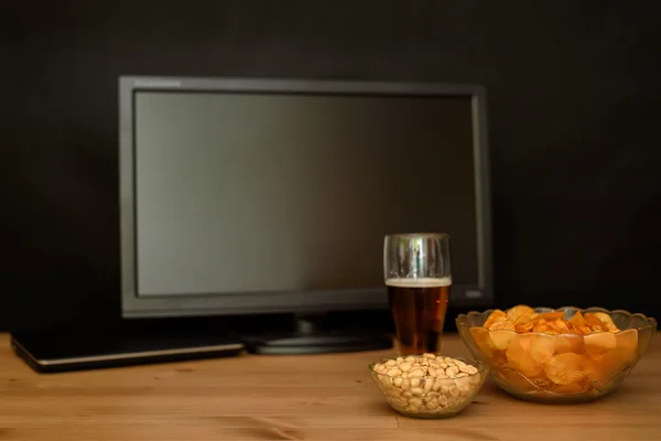 TV and computer with unhealthy snack on table isolated on black