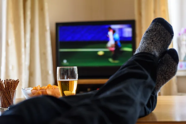 Television, TV watching (football match) with feet on table and