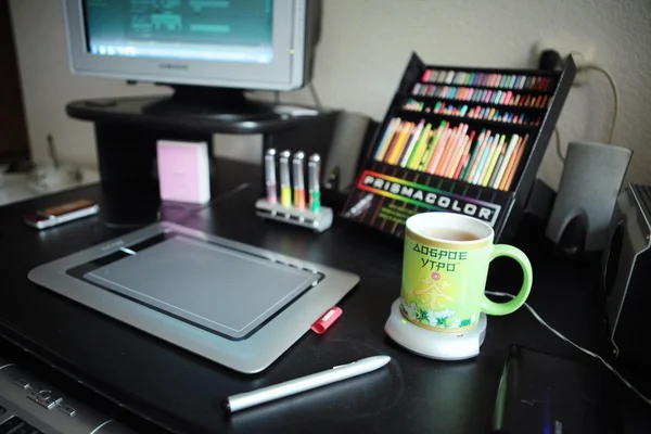 Computers, cup of tea and pencils on table