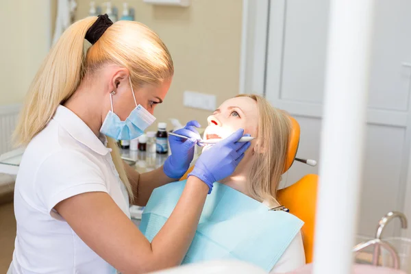 Woman dentist treats a patient - face side