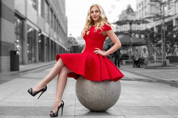 Woman in red dress sitting on sphere BW