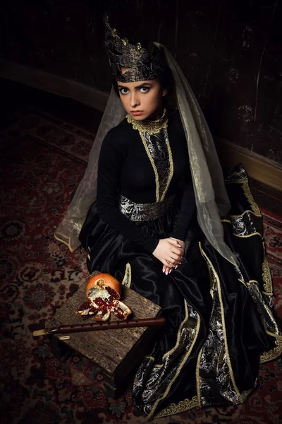 Beautiful girl in armenian national dress sit with pomegranate and duduk in studio