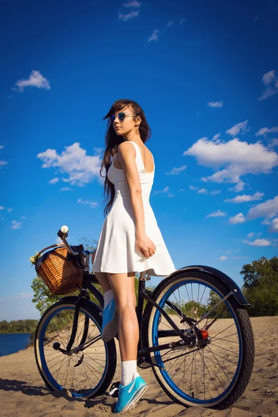 Beautiful young woman on the beach with cruiser bicycle