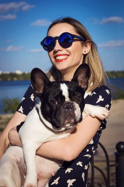 Beautiful young woman on the beach with french bulldog