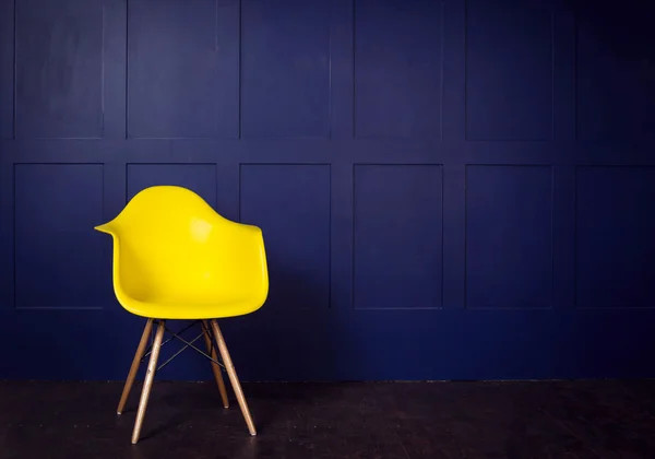 Interior design scene with a modern yellow chair on blue wall