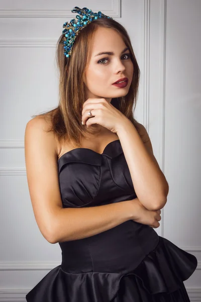 Beautiful woman in black dress with crown on head