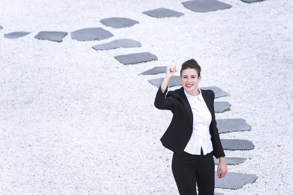 Modern business woman raising hand walking on the path