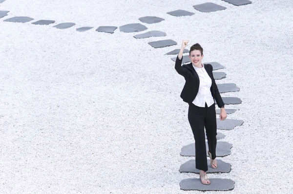 Modern business woman raising hand walking on the path