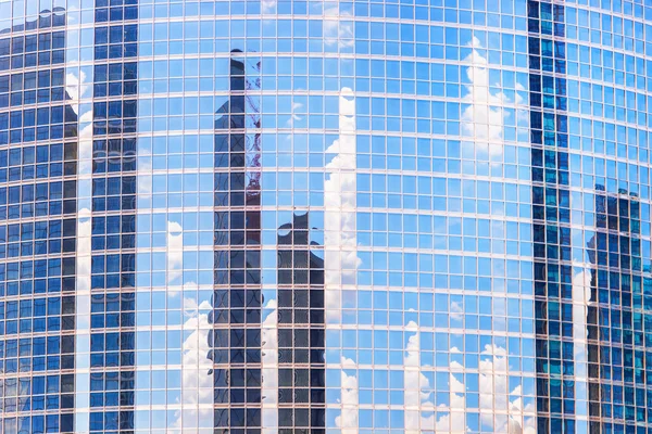 The reflection of cloud and buildings in the windows of modern o