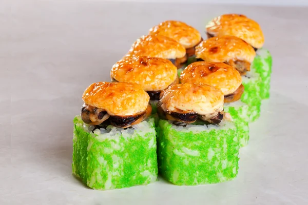 Sushi roll with mussels and green tobiko caviar caps baked cheese on a white background isolated close-up for the menu