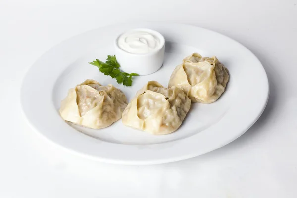 Manti dumplings ravioli great big huge with sour cream and parsley on a plate menu for the cafe restaurant isolated white background