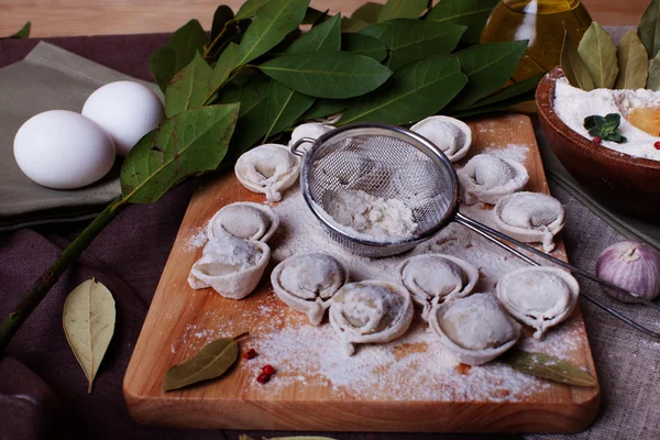 Dumplings on the board with flour and strainer manual modeling ravioli bay leaf