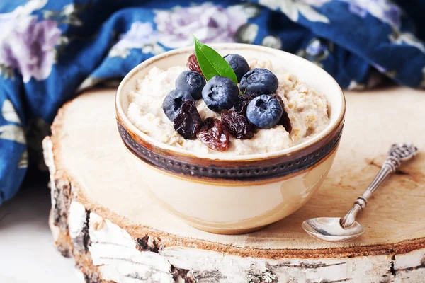 Oatmeal porridge with berries still life, blueberries, raisins, birch, cut down