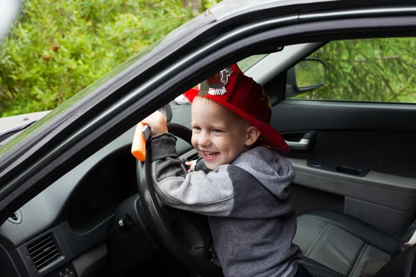 Baby boy firefighter fireman suit, smiling, car, wheel, driver, helmet