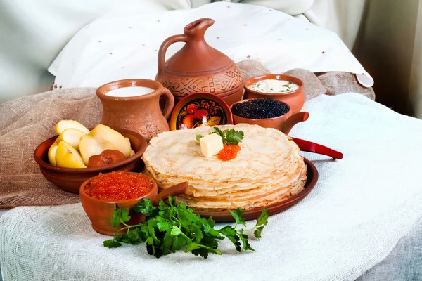 Stack of pancakes with red and black caviar in a rustic still life