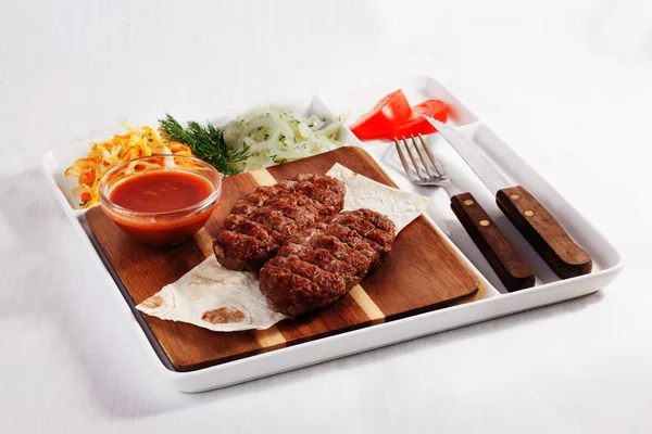 Skewers meat, beef, with coleslaw, tomato, sauce on the board, paper, plate, fork, knife, isolated, menu