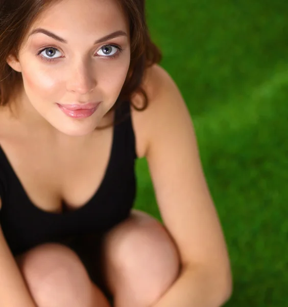 Woman sitting with crossed legs on the green grass