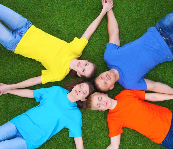 Group of young people lying on green grass