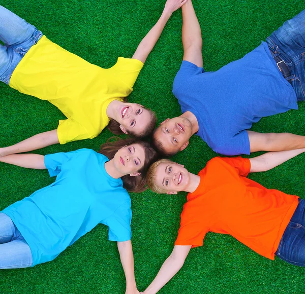 Group of young  people lying on green grass