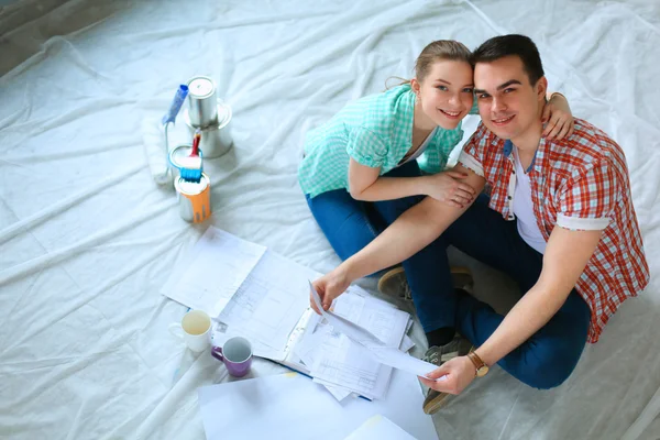 Young couple sitting on floor with apartment plan