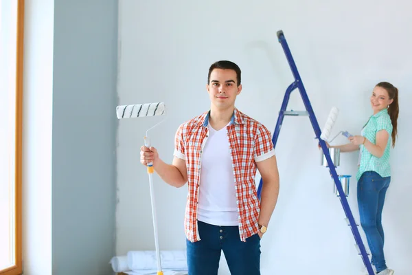 Portrait of happy smiling young couple  painting interior wall of new house