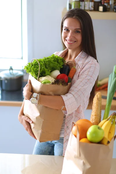 Young woman holding grocery shopping bag with vegetables