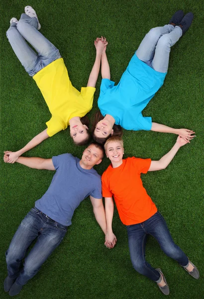 Group of young people lying on green grass