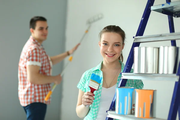 Portrait of happy smiling young couple  painting interior wall of new house