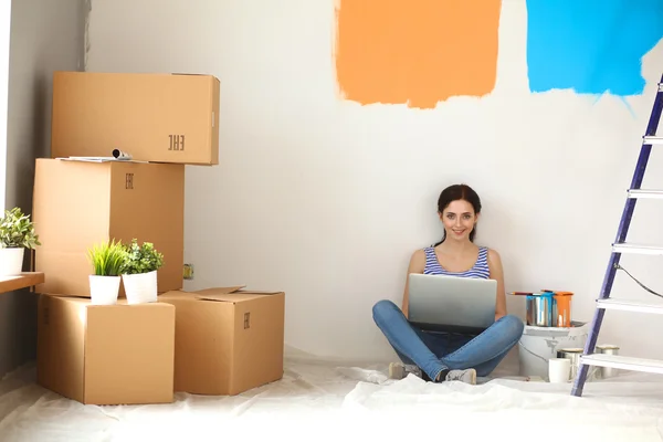 Young woman portrait while painting new apartment ,sitting with laptop
