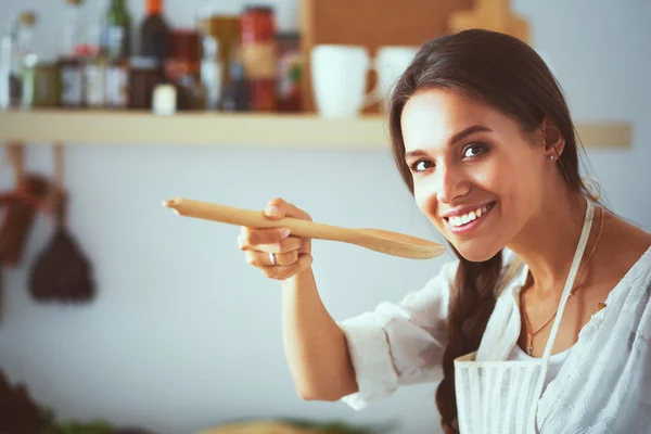 Cooking woman in kitchen with wooden spoon