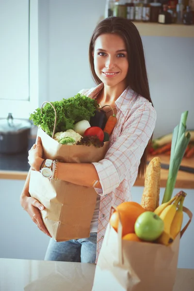 Young woman holding grocery shopping bag with vegetables