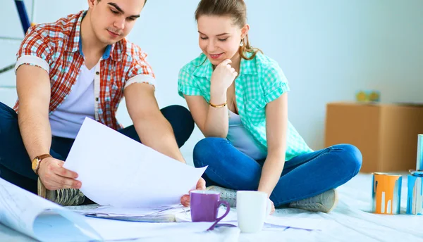 Young couple sitting on floor with apartment plan