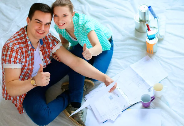 Young couple sitting on floor with apartment plan