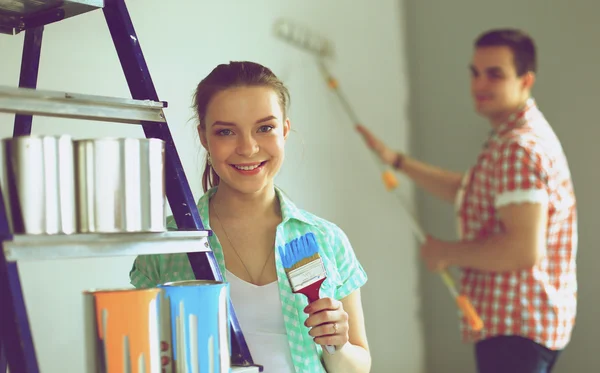 Portrait of happy smiling young couple  painting interior wall of new house