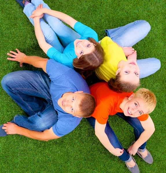 Group of young  people lying on green grass