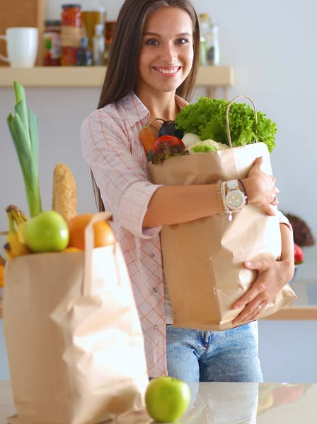 Young woman holding grocery shopping bag with vegetables