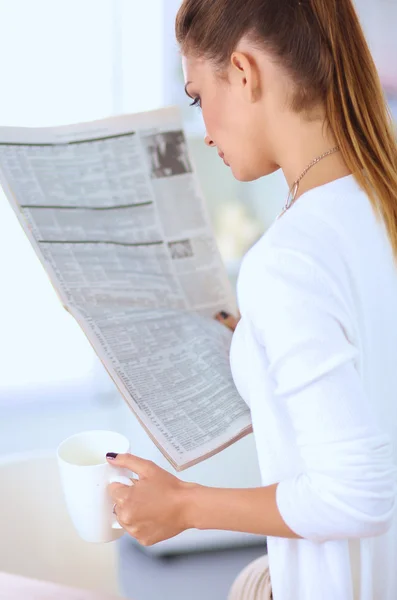 Cute businesswoman holding newspaper sitting at her desk in bright office