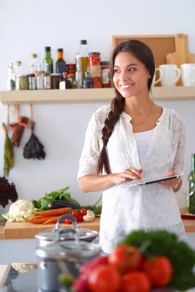 Young woman using a tablet computer to cook in her kitchen