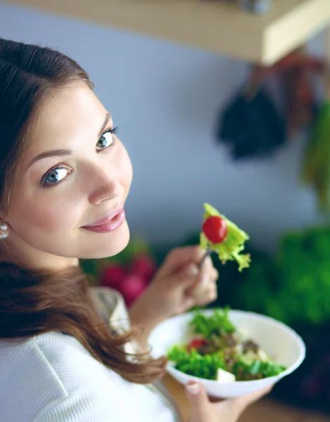 Young woman eating salad and holding a mixed salad