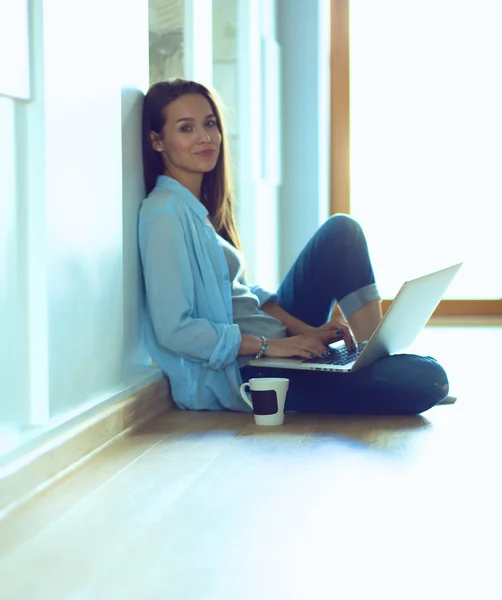 Young beautiful woman at home sitting on the floor with laptop