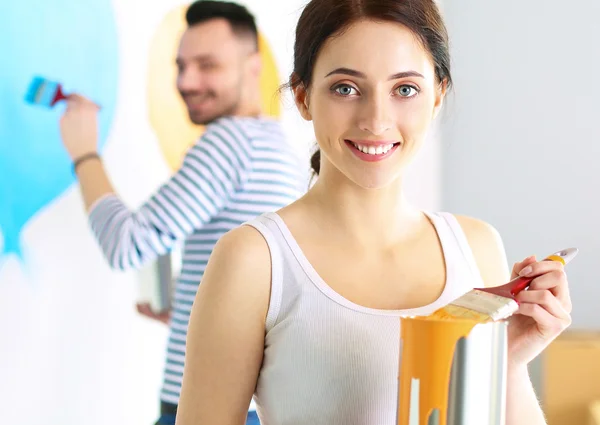 Portrait of happy smiling young couple painting interior wall of new house