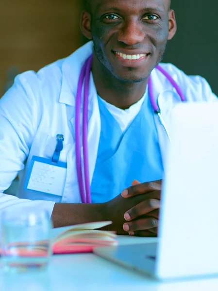 Young african doctor working on laptop at desk