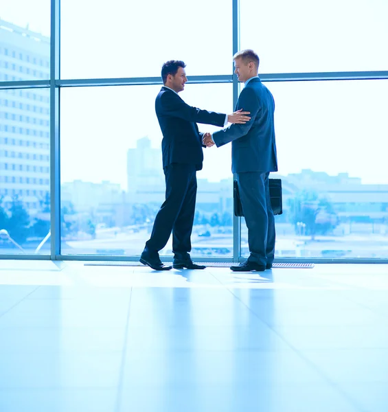 Full length image of two successful business men shaking hands with each other